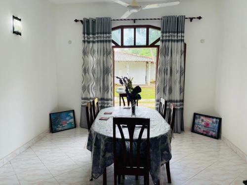 uma sala de jantar com uma mesa e cadeiras e uma janela em Pasidu Villa em Kalutara