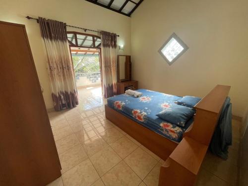 a bedroom with a bed with blue sheets and a window at Pasidu Villa in Kalutara