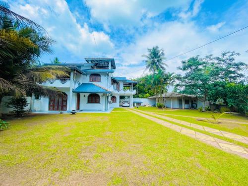 a large white house with a grass yard at Pasidu Villa in Kalutara