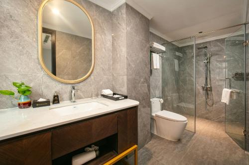 a bathroom with a sink and a toilet and a mirror at MAY DE VILLE Lakeside Hotel in Hanoi