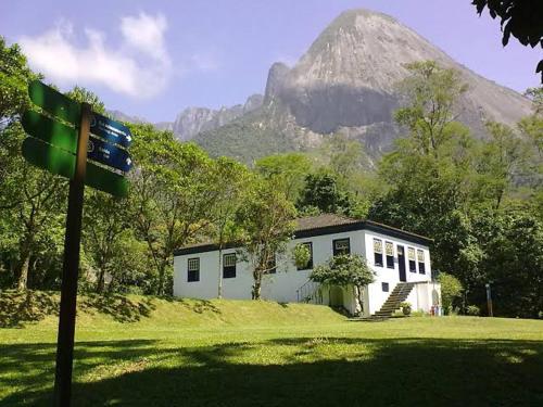 a small white house with a mountain in the background at Vale da Paz in Guapimirim