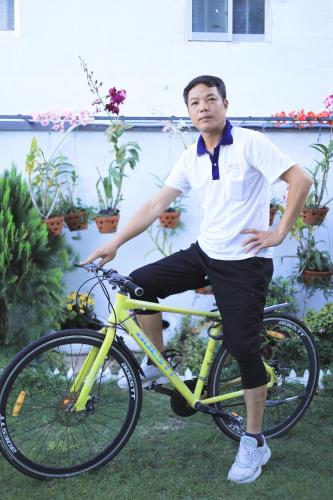 a man is sitting on a yellow bike at Villa homestay Misa in Phan Thiet