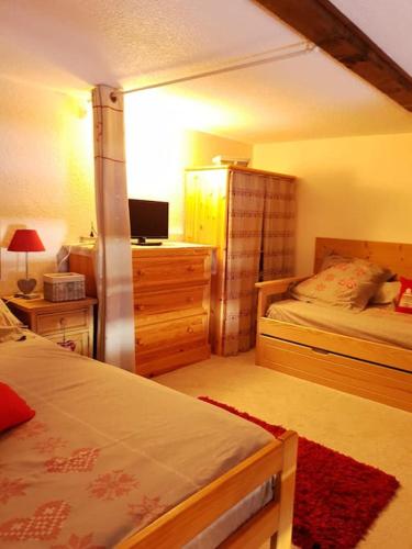 une chambre avec deux lits et un bureau avec une télévision dans l'établissement Coeur de montagne, à La Toussuire