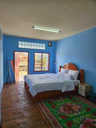 a bedroom with a bed and a blue wall at Paksong Brand New- Two-story house in Paksong