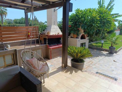 a patio with a swinging chair and a fireplace at Villa Fay in Lardos