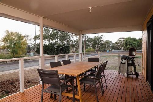 a wooden table and chairs on a deck with a grill at Long Island Retreat II (by the river with wi-fi) in Murray Bridge