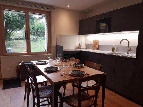 a kitchen with a wooden table with chairs and a dining room at Le Cottage in Sorans-lès-Breurey