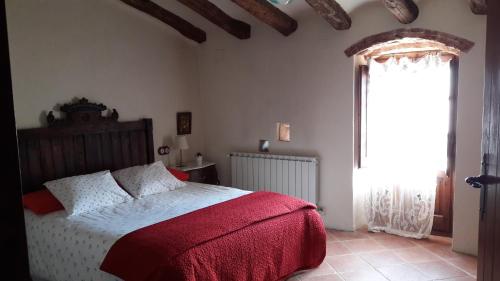 ein Schlafzimmer mit einem Bett mit einer roten Decke und einem Fenster in der Unterkunft Masia Sapera in Pontons