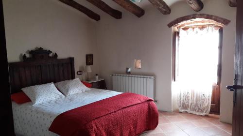 a bedroom with a bed with a red blanket and a window at Masia Sapera in Pontons