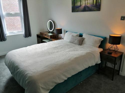 a bedroom with a large bed with two lamps and a mirror at The Snug Centre of Morpeth in Morpeth