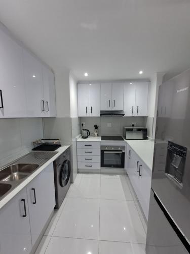 a white kitchen with white cabinets and appliances at North beach summer sands holiday in Durban