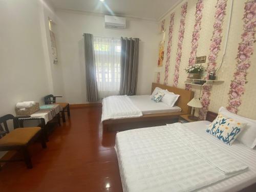 a room with four beds and a window with curtains at Villa sân vườn Misa in Phan Thiet