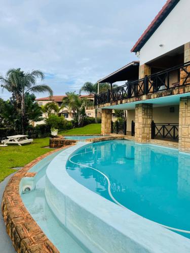 a swimming pool in front of a house at Privately Owned Apartment at Ocean View Villas in Port Edward