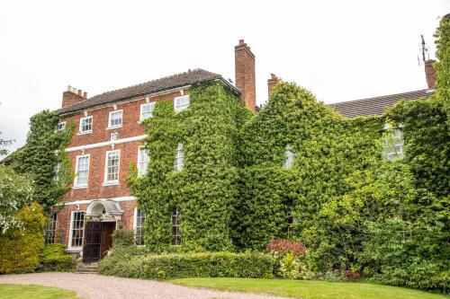 an ivy covered brick building with a yard at Park House Hotel in Shifnal