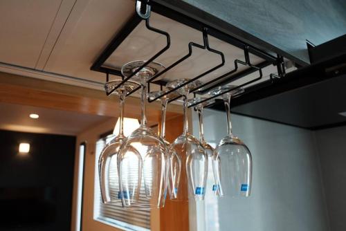 a group of wine glasses hanging from a rack at 【 STAY Chill ~omura~】長崎空港から車で10分！ in Omura