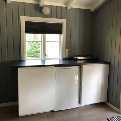 a kitchen with white cabinets and a window at Sølvgarden Camping in Rysstad