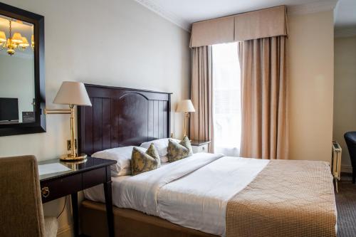 a hotel room with a bed and a desk and a window at Park House Hotel in Shifnal