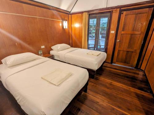 two beds in a small room with wooden walls at Ziggy Stardust in Ko Phayam