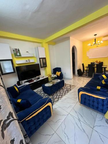 un soggiorno con divani blu e una TV di Ramakyri room a Douala
