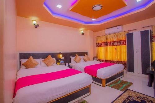 una camera d'albergo con due letti con lenzuola rosa e bianche di RINGJI PALACE a Kakarvitta