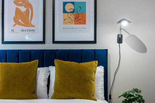 a bed with a blue headboard and some framed pictures at Host & Stay - Ropewalks Quarters in Liverpool