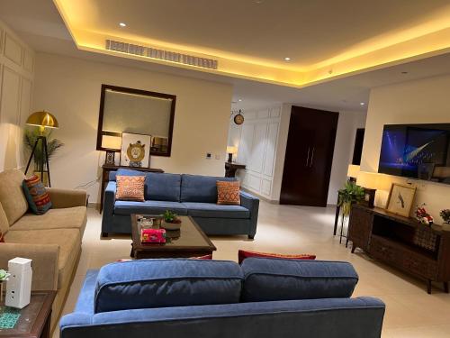 sala de estar con sofás azules y TV de pantalla plana en One Constitution Avenue 3BHK Scenic Suite, en Islamabad
