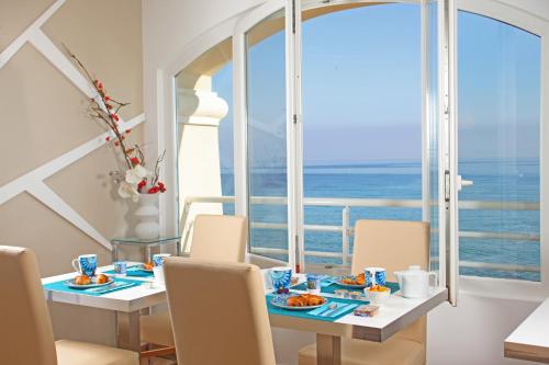 a dining room with a view of the ocean at Hotel Beau Rivage in Algajola
