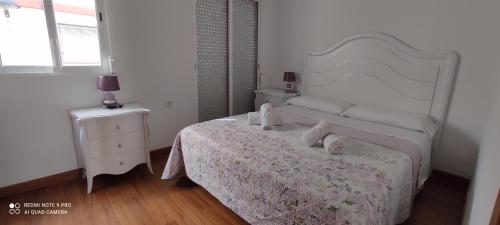 a white bedroom with a bed and a night stand at Mi pequeña terraza in Alaquas