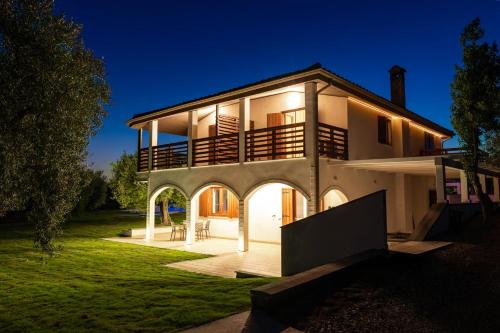 a large white house with a porch at night at Ollu e Stentu in Dolianova