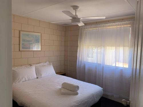 een slaapkamer met een wit bed met een hoed erop bij Harbour View 49 Urch Street Unit 2 in Geraldton