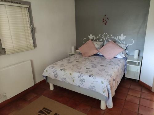 een slaapkamer met een bed met roze kussens erop bij Cosy rez-de-jardin de villa in Brignoles