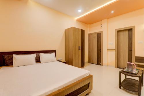 een slaapkamer met een groot bed en een tafel bij OYO Hotel Ambika Palace in Patna