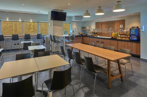 a cafeteria with tables and chairs and a kitchen at City Express by Marriott Guaymas in Guaymas