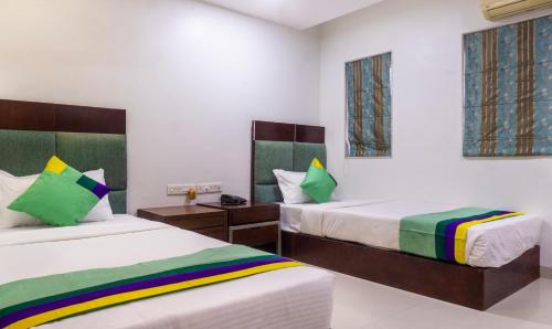 a bedroom with two beds and two windows at Treebo Bhairavee, Baner in Pune