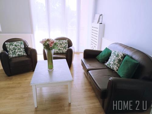 - un salon avec deux canapés et une table fleurie dans l'établissement Echappée Belle à Montauban - parking - centre ville, à Montauban