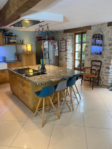 une cuisine avec un grand îlot doté de tabourets de bar bleus dans l'établissement Dordogne Farmhouse, à Beaulieu-sur-Dordogne