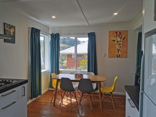 Modern home in Dunedin في دنيدن: مطبخ مع طاولة طعام وكراسي