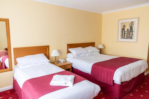 a hotel room with two beds and a mirror at Tiverton Hotel Lounge & Venue in Tiverton