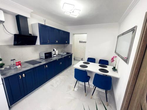 una cucina con armadi blu e tavolo e sedie bianchi di Apartament Premium Isabella a Arad