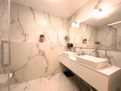Baño con 2 lavabos y paredes de mármol en Bcn Centric Rooms, en Barcelona