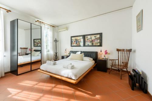 1 dormitorio con cama, silla y espejo en [Heart of Lucca] Style whitin the walls, en Lucca