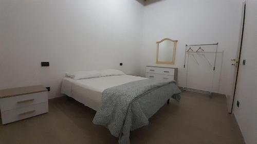 a white bedroom with a bed and a dresser at Appartamento Il Pozzo in Capannori