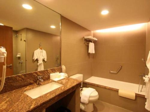 ein Badezimmer mit einem Waschbecken, einem WC und einem Spiegel in der Unterkunft Garden Orchid Hotel 