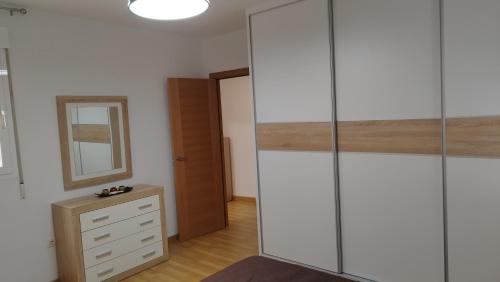 1 dormitorio con armario blanco alto y cómoda en Apartamento Fuente del Genil., en Fuente Vaqueros