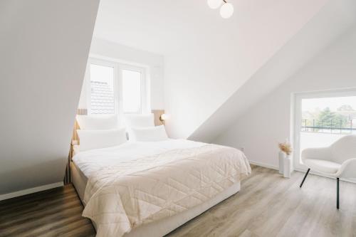 1 dormitorio blanco con 1 cama y 1 silla en Küsten Suite de See - Suite 4 seitliche Deichlage, Balkon, 89qm, en Greetsiel