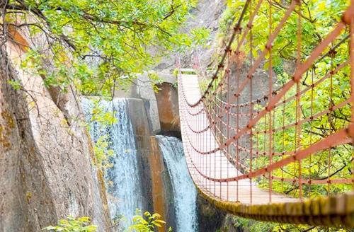 a swinging bridge over a waterfall in a waterfall at Casa Jaime in Monachil