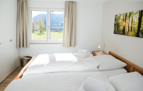 Duas camas num quarto branco com uma janela em Ferienhaus mit Garten Tgease Schilendra-Lantsch-Lenz-Lenzerheide em Lenz