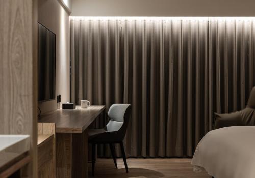 a hotel room with a desk and a bed and a bedroom at Spring Rhapsody Hotel in Taichung