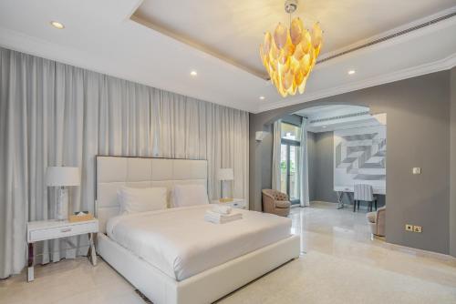 a bedroom with a large white bed and a chandelier at Maison Privee - Prvt Pool & Beach Access in Luxury Palm Jumeirah 6BR Villa in Dubai