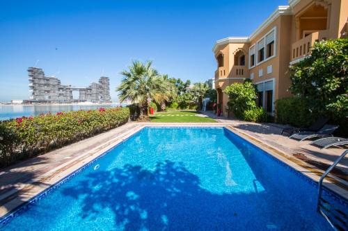 a swimming pool in front of a building with the ocean at Maison Privee - Prvt Pool & Beach Access in Luxury Palm Jumeirah 6BR Villa in Dubai